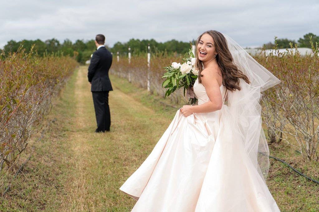 bride in greenery field laughing while turning towards the camera